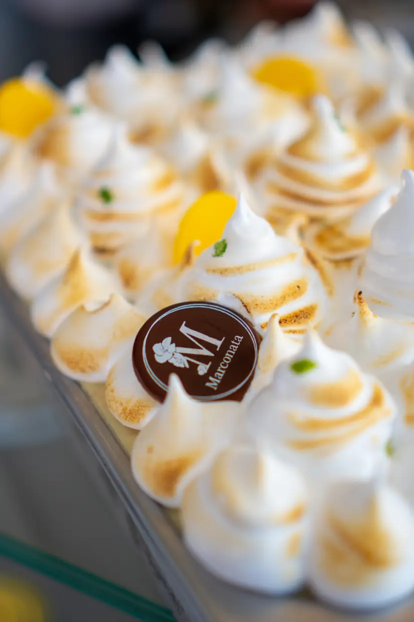 Helado cubierto de picos de merengue tostado, con rodajas de limón y una placa de chocolate con la M de Marconata