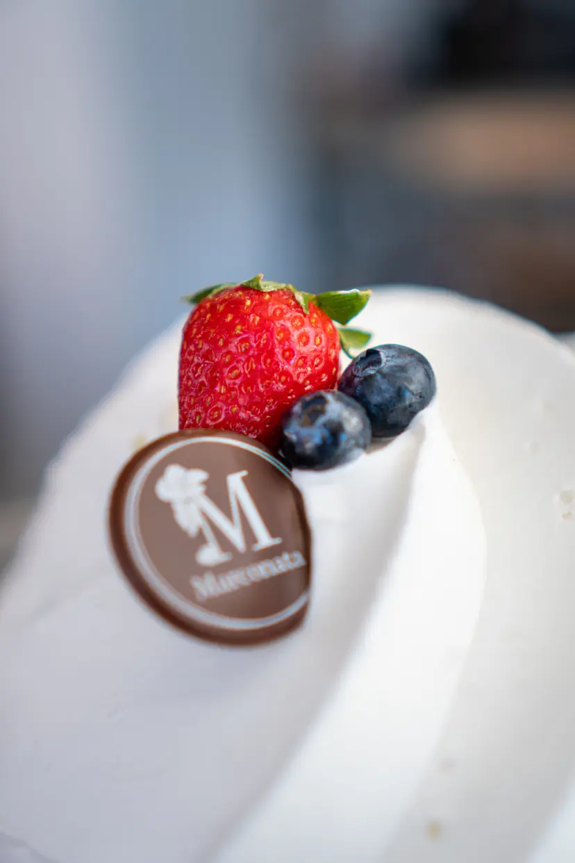 Helado blanco con una fresa, dos arándanos y una placa de chocolate con la M de Marconata