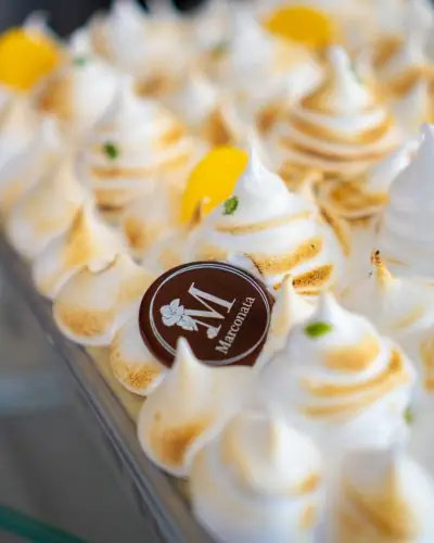 Helado cubierto de picos de merengue tostado, con rodajas de limón y una placa de chocolate con la M de Marconata