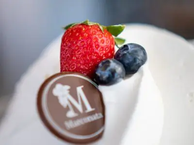 Helado blanco con una fresa, dos arándanos y una placa de chocolate con la M de Marconata